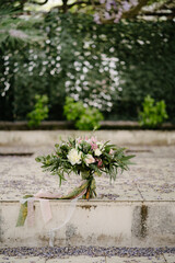 bridal bouquet of white and pink roses, protea, eucalypt tree branches, veronica and peonies with long silk ribbons outdoor