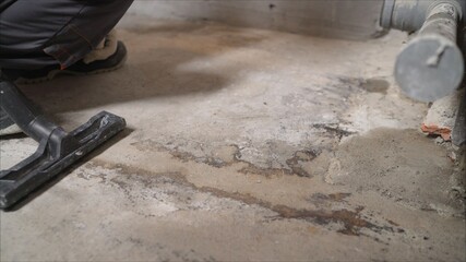 A worker vacuums a concrete floor with a vacuum cleaner. vacuum cleaner construction on the background of concrete walls and floors