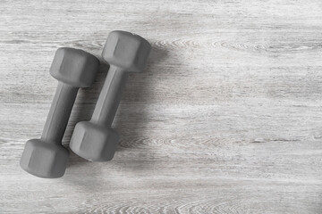 Gray dumbbells on a wooden background for fitness classes. Space for text.