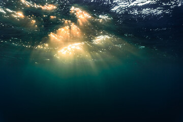 Rays of light shining through the surface of the atlantic ocean, into the deep, blue and dark abyss
