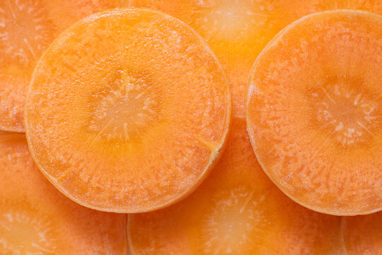 Closeup bright round carrot slices, Vegetable pieces background. Orange monochrome horizontal shot for creative desigh about organic vegetable, healthy food, ingredient for salad, vegeterian dishes