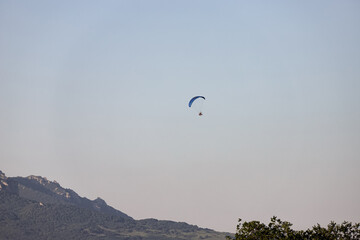 Tourists fly on motorcycle paragliders over mountains