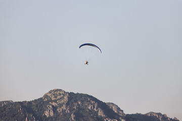 Tourists fly on motorcycle paragliders over mountains
