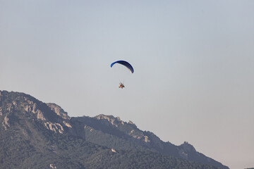 Tourists fly on motorcycle paragliders over mountains