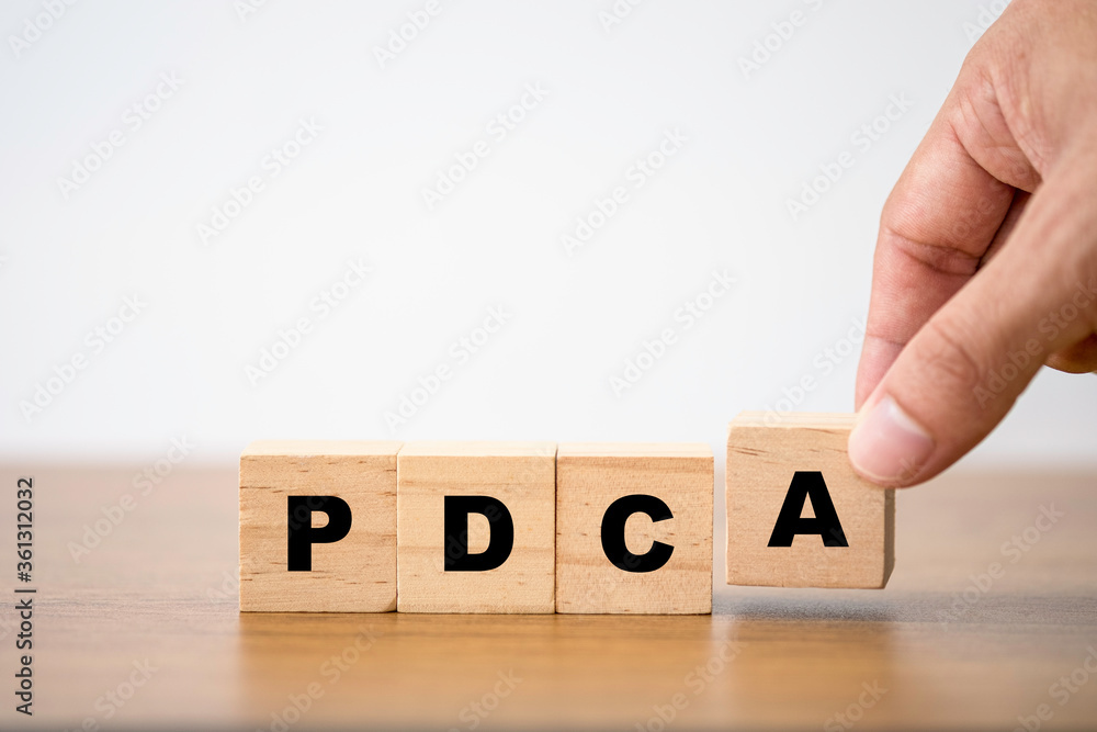 Poster hand putting p d c and a which print screen on wooden cube block. plan do check and action is contin