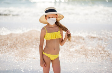 Beautiful girl alone on the beach in a medical mask. A crisis. How to wear a mask when traveling....