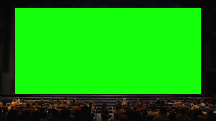 Viewers sitting in front of a big chroma key screen in the auditorium. Audience applauding, light...