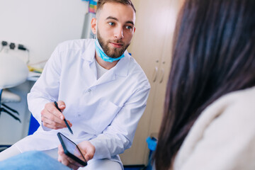 Dentist and patient look together on X-ray image of the dentitio