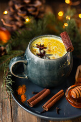 Golden milk, turmeric latte in grey mug. Spicy traditional Indian drink. Healthy natural healing curcuma beverage, alternative medicine. Close up, front view, rustic wooden background