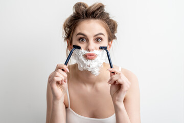 Beautiful young caucasian woman shaving her face by two razors on white background. Pretty woman...