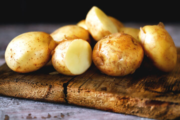 Selective focus. Young raw potato on a wooden surface. Fresh potato harvest.
