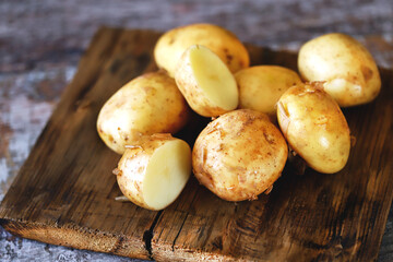 Selective focus. Young raw potato on a wooden surface. Fresh potato harvest.