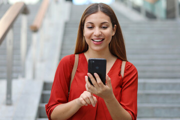 Portrait of beautiful woman walking down the stairs holding her phone