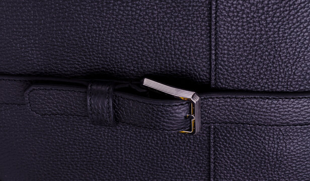 Silver metal clasp on a black leather belt against Genuine leather texture.