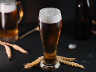 Cold light beer in a glass on a dark table.