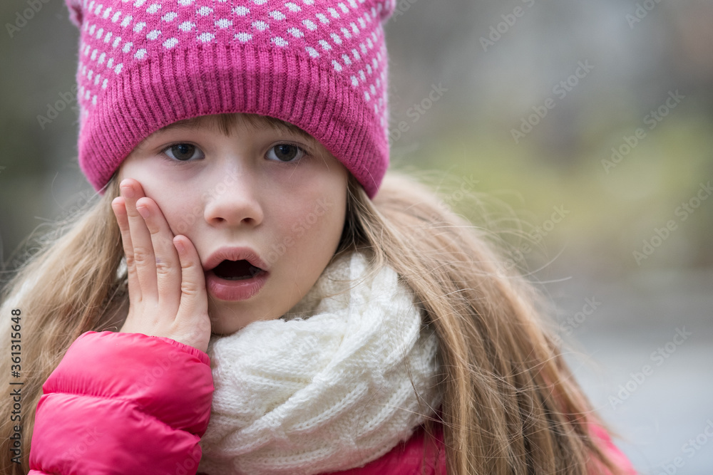 Wall mural pretty child girl in warm knitted winter clothes outdoors.