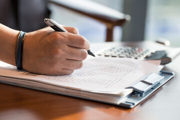 man hand with pencil writing on document.