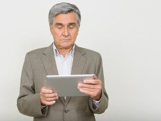 Portrait of handsome senior businessman using digital tablet