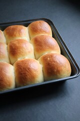 Freshly baked homemade Mumbai style golden Ladi pav or soft dinner bread roll in a baking tray. made out of all-purpose flour, yeast, milk and salt.  Ideal for pav bhaji or missal pav. Copy space.
