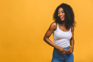 Portrait of beautiful positive african american black woman standing isolated over yellow background.