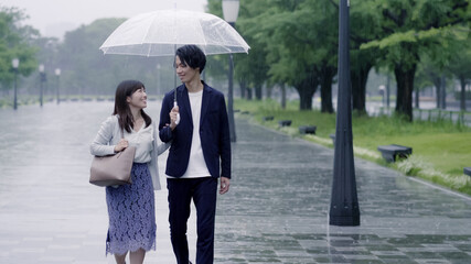 雨の日に傘を差してデートするカップル