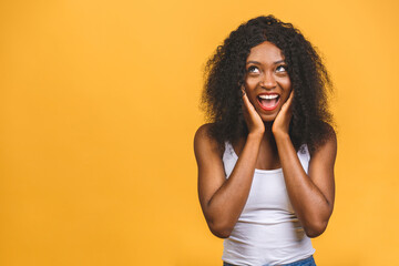 Surprised happy young african american woman stands in big shopping mall, glad to see big discounts on clothes, expresses shock, keeps hands near head, going to spend much money today.