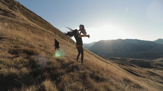 A girl picks up a child in her arms on the top of a mountain