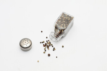 Black pepper falls out of the pepper shaker on a white background