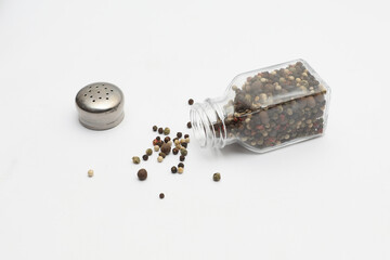 Black pepper falls out of the pepper shaker on a white background