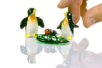 Fototapeta premium Two penguins ladybug and a master's hand ceremony.
