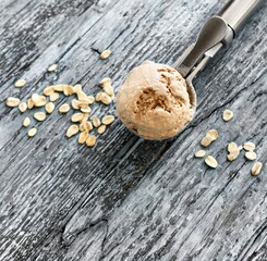 Oatmeal ice cream ball in an ice cream spoon and oatmeal flakes on a blue wooden background. Top view