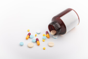 The medicine bottle fell and the pill was strewn on a white background.