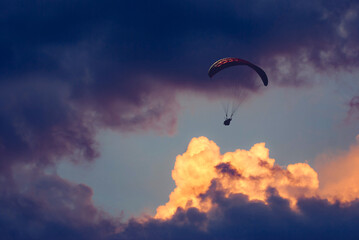 Paraglider silhouette flying in a cloudy sky