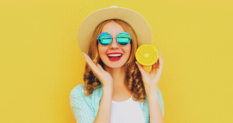 Summer portrait of happy smiling woman with fruits slice of orange wearing straw hat, sunglasses on yellow background