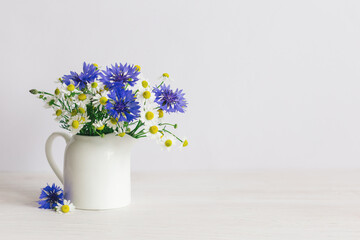 Romantic bouquet of the meadow flowers in a jar on a white background.