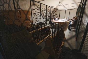 Automatic rifles lie foreground on the shelf in the armory