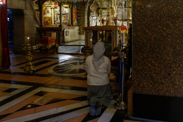 The believer woman kneels and prays in the Church of the Holy Sepulchre in Christian quarter in the old city of Jerusalem, Israel