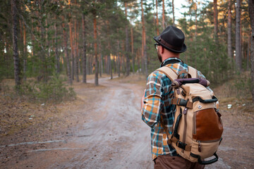 Naklejka premium camping in the woods. a man in a hat with a backpack walks through the woods.