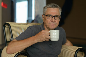 Handsome senior man drinking coffee and relaxing at home indoors