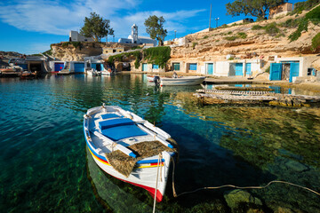 Fototapeta na wymiar Fishing boats moored in crystal clear turquoise sea water in harbour in Greek fishing village of Mandrakia, Milos island, Greece. Horizontal camera pan