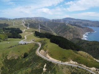 Aerial view of wind turbines generating power on a green wind farm under the blue sky