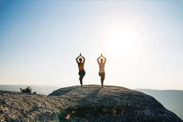 Two girls do yoga in the mountains. Sport and outdoor recreation