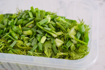 Finely chopped herbs, onions, parsley, dill in a container