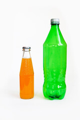 clear glass bottle with orange drink and green plastic bottle