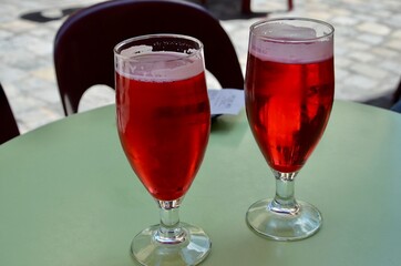 Traditional french Monaco cocktails on a green table, two glasses with red alcoholic beverages, blurred background