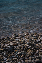 A wave rolls over the rocky shore. Pebble beach. Seashore.