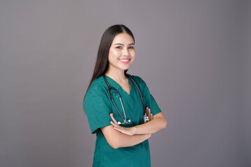 a female doctor wearing a green scrubs and stethoscope is on grey background studio