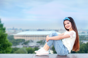 Beautiful teenage girl student the city at sunset panorama