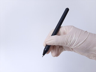 A hand with white latex glove holding a black pen, write in the air. Isolated on a white background, side view