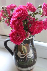 

A bouquet of small roses stands in a ceramic vase. The flowers are delicate and smell pleasant